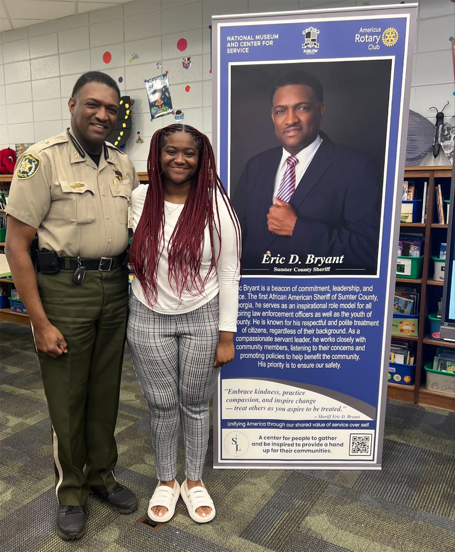 Student with Sheriff Eric Bryant standing by banner stand for Eric D. Bryant, Sumter County Sheriff, at Furlow Charter School's Museum for Service