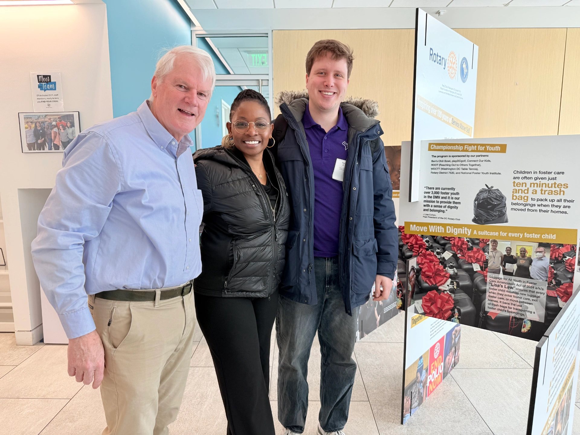 Group photo of three people near signs set up for museum exhibit