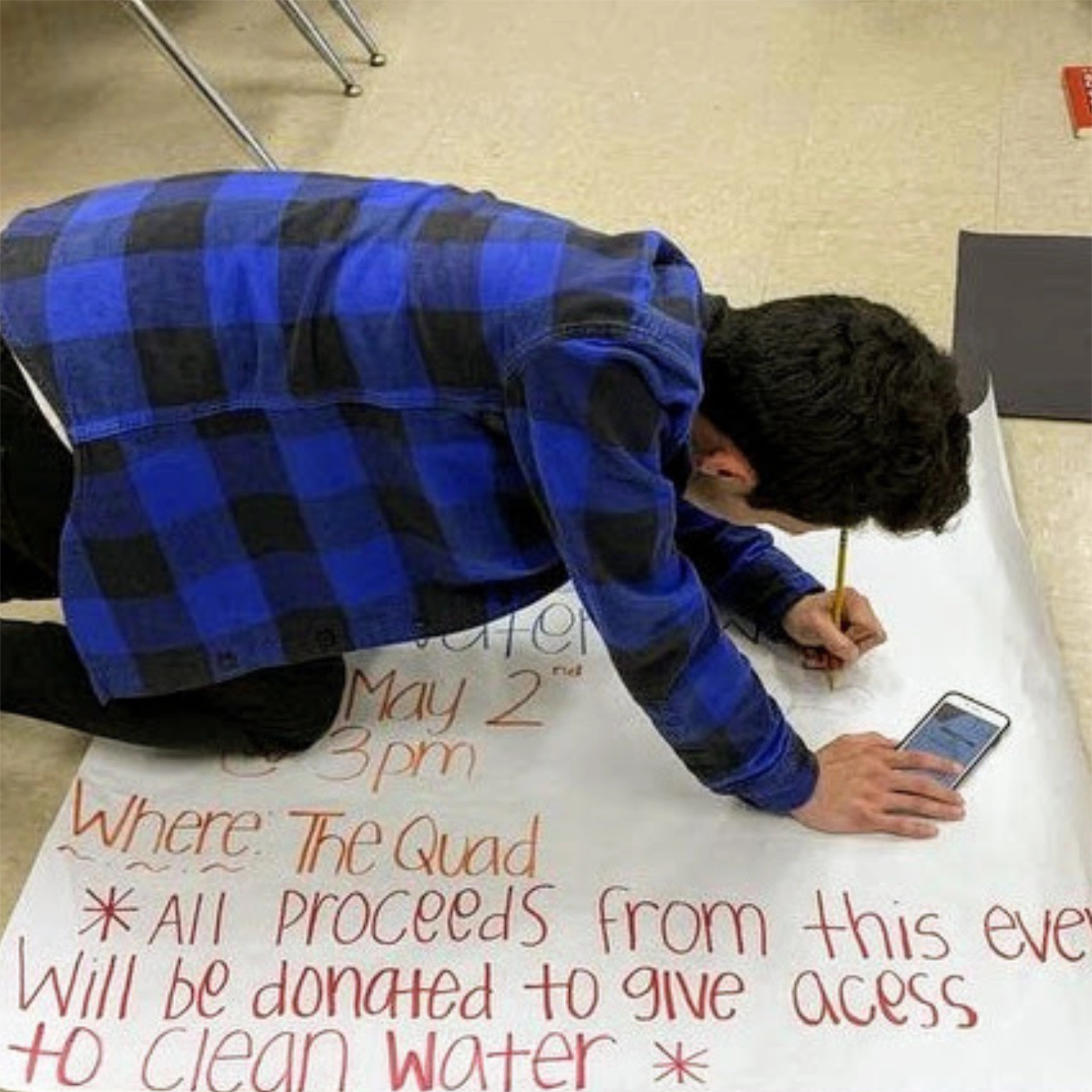 Student writing poster on floor