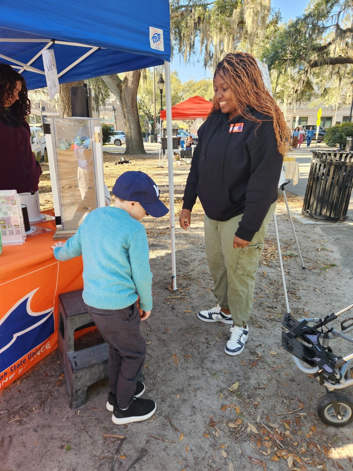 Tanisha educating the public about microplastics and plastic pollution in sediment using a display