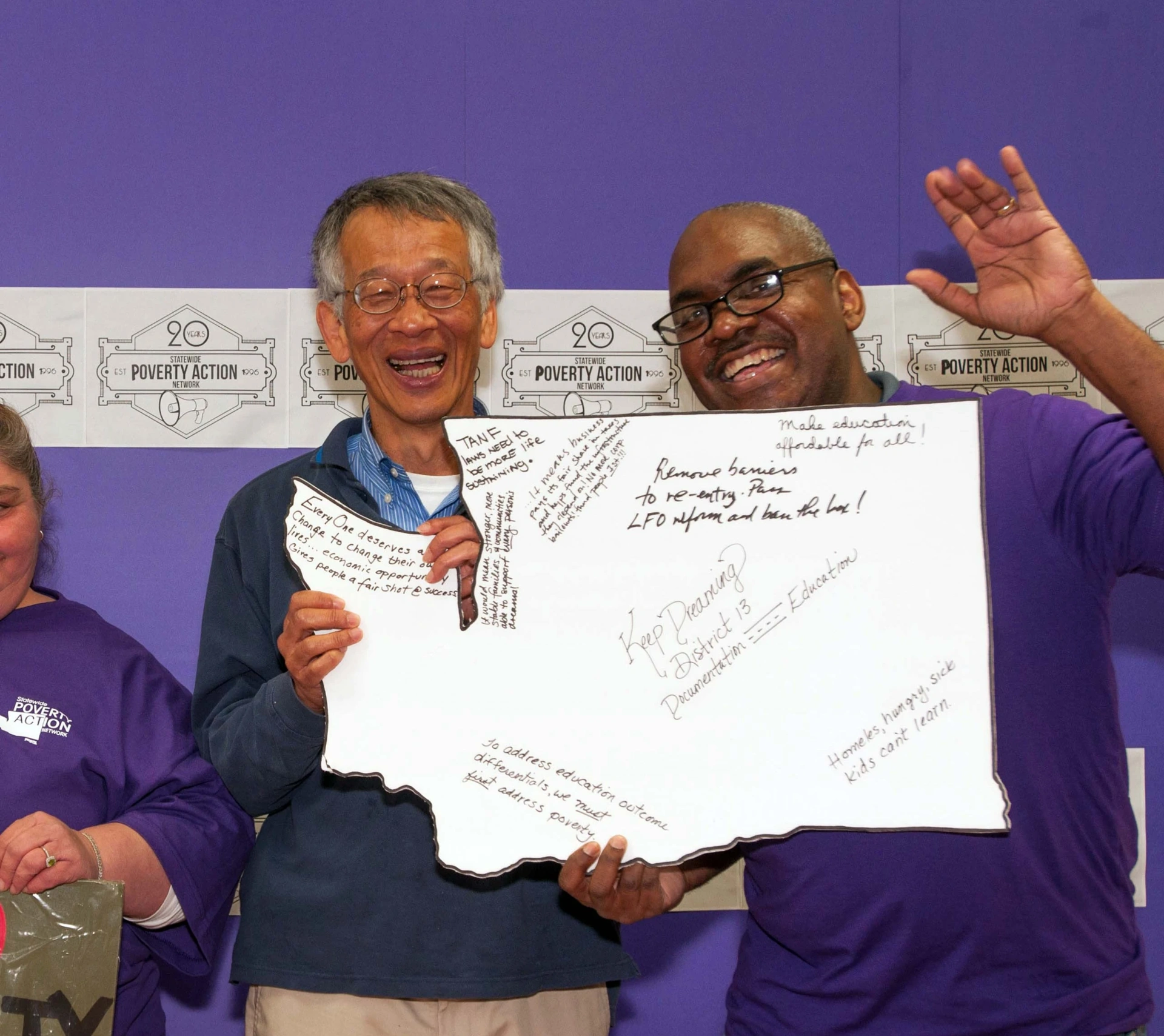 Tony posing with person and holding sign in shape of state of Washington at Statewide Poverty Action Network event