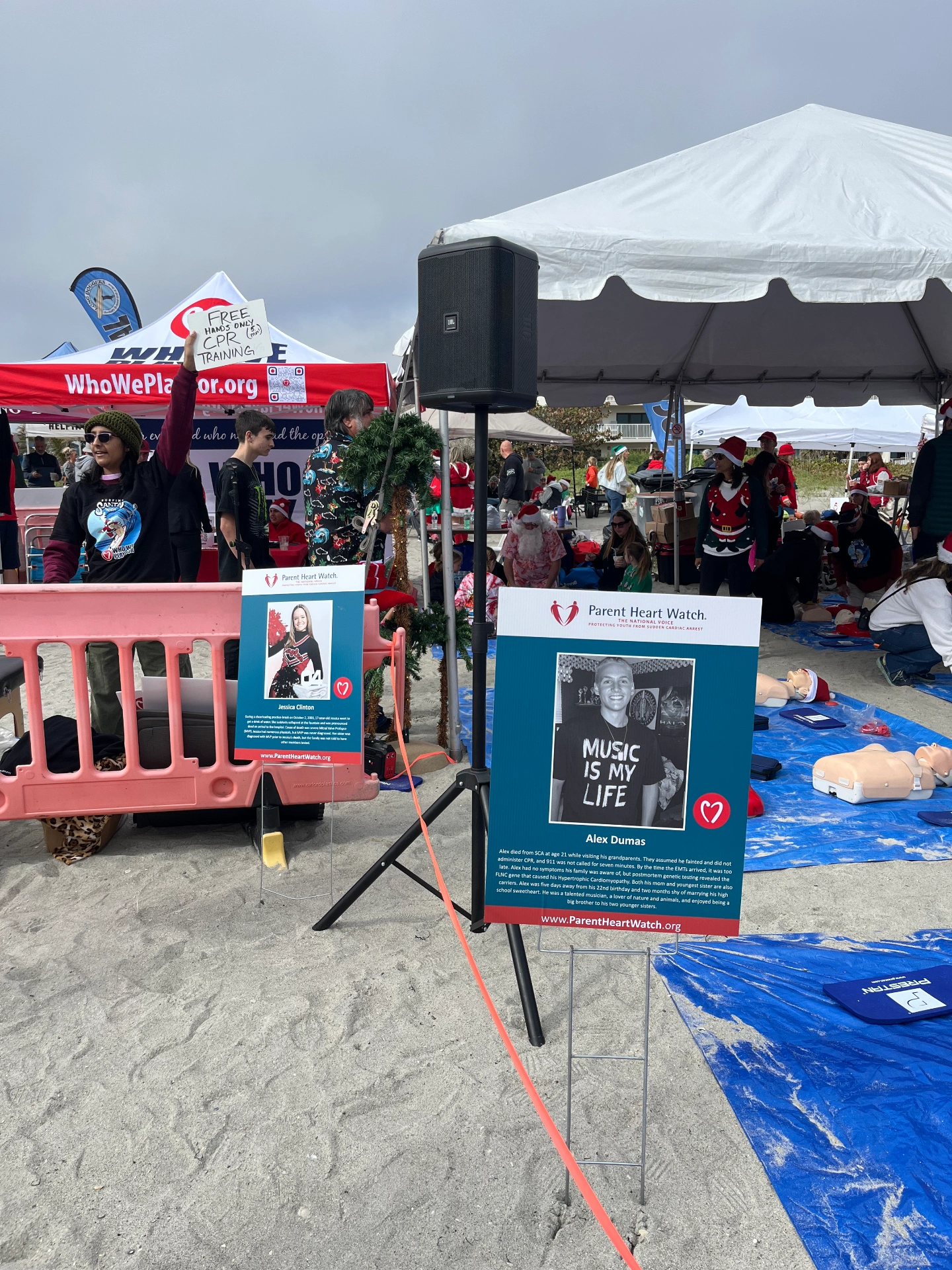 Signs posted at Who We Play For event on beach with tributes to Alex Dumas and Jessica Clinton