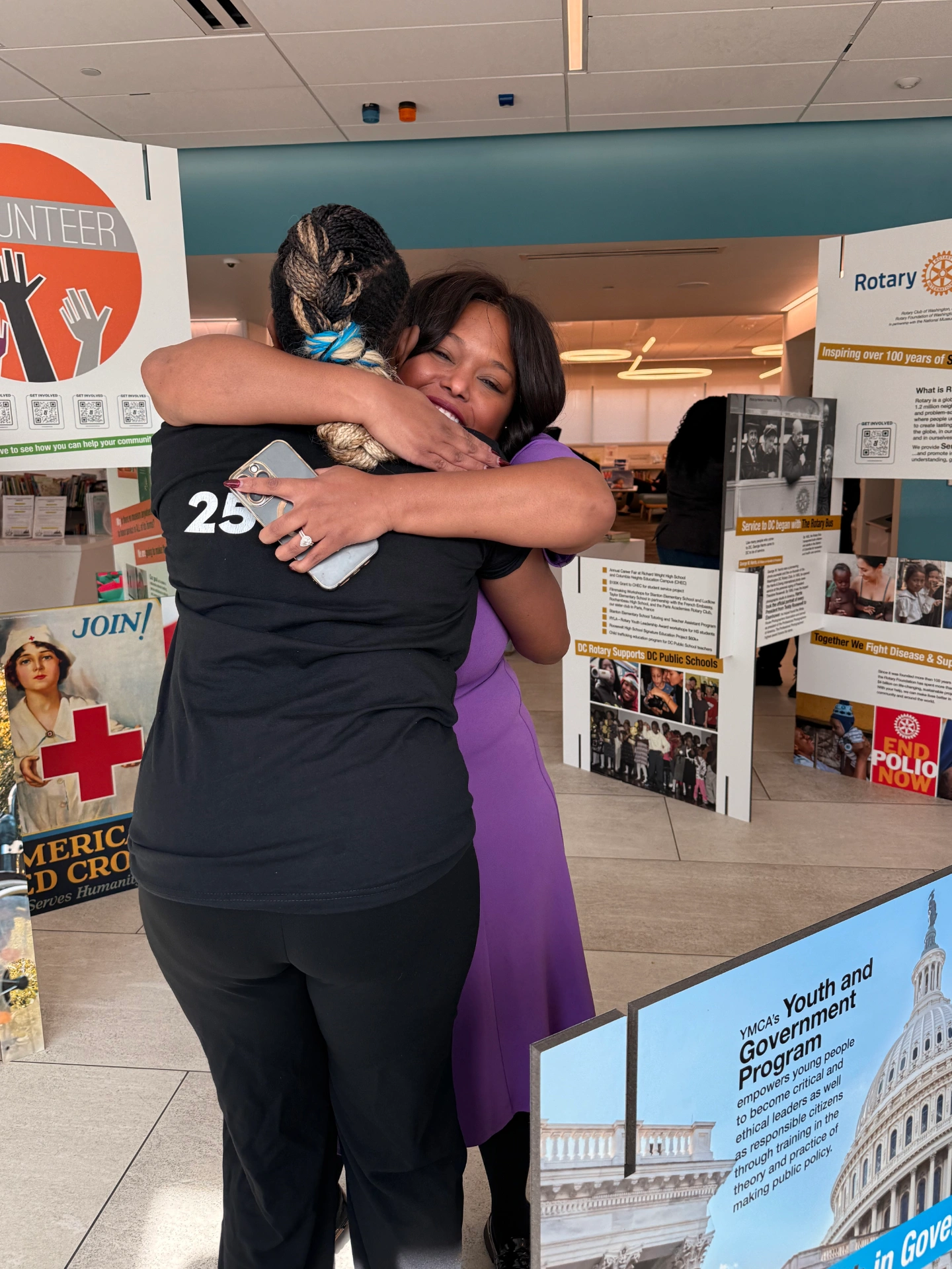 Two women hugging near signs set up for museum exhibit