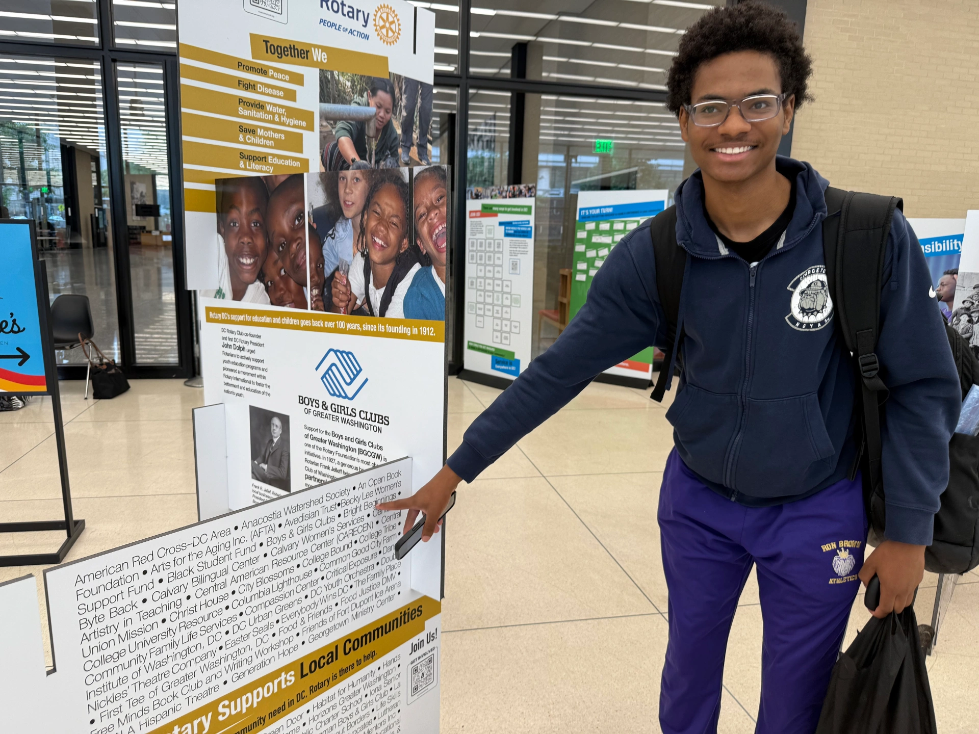 Young man pointing at Rotary International sign at exhibit