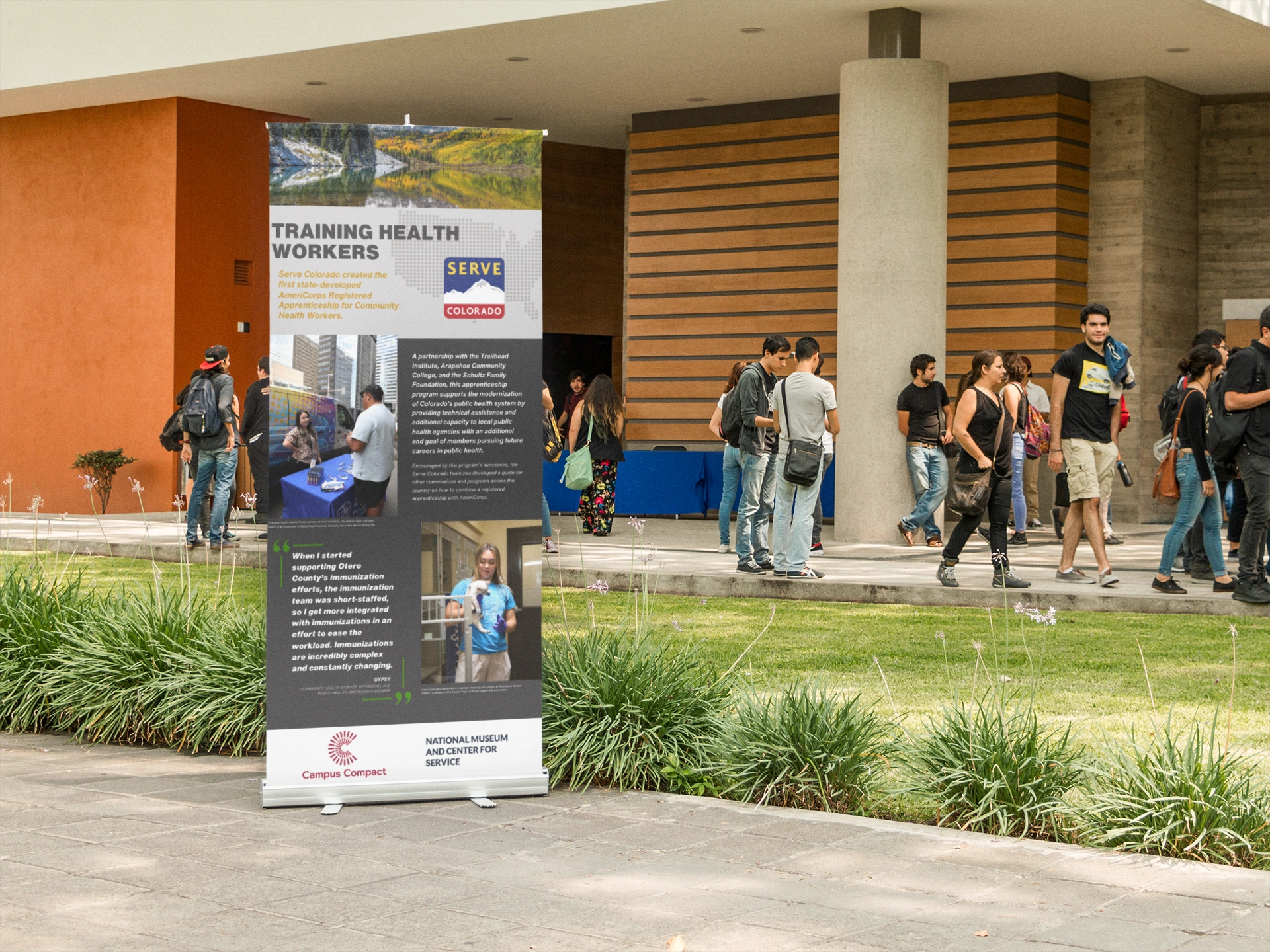 Crowd of students walking in outside campus walkway near banner exhibit