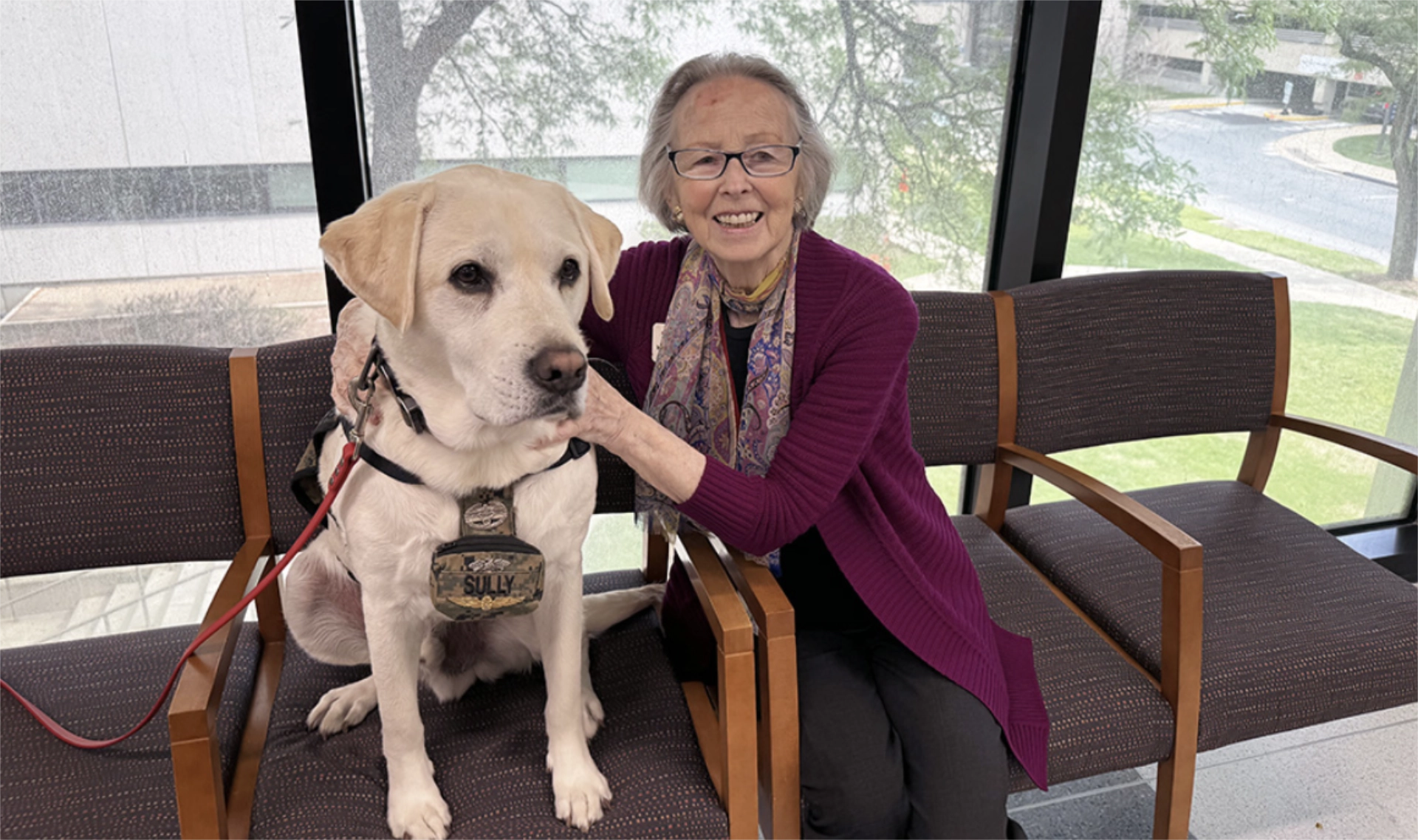 Dr. Inge Guen sitting in row of chairs with a service dog