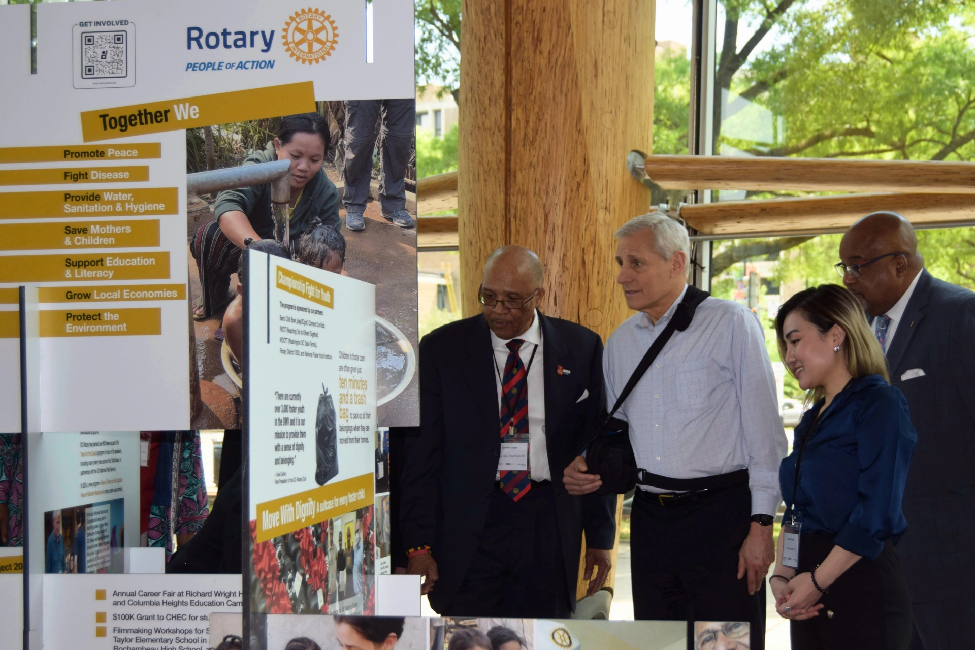 CEO of Rotary International John Hewko with others reading signs at NMCFS exhibit showcasing Rotary International