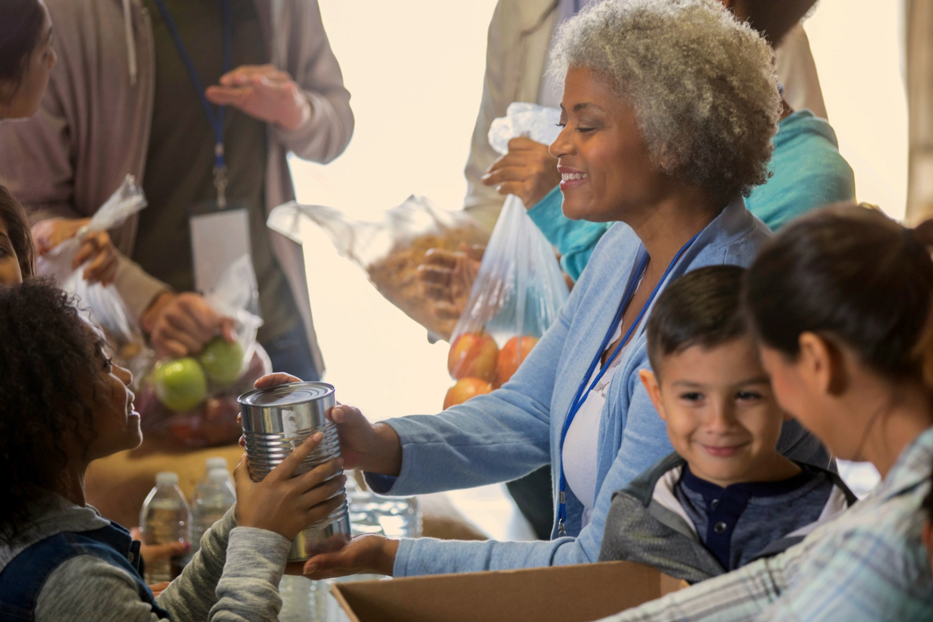 Woman collecting a canned good donation from a smiling child at a food drive